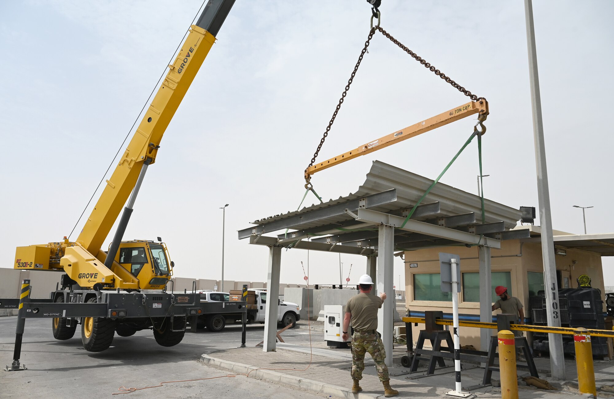 A photo of Airmen using a crane to set a sunshade in place.
