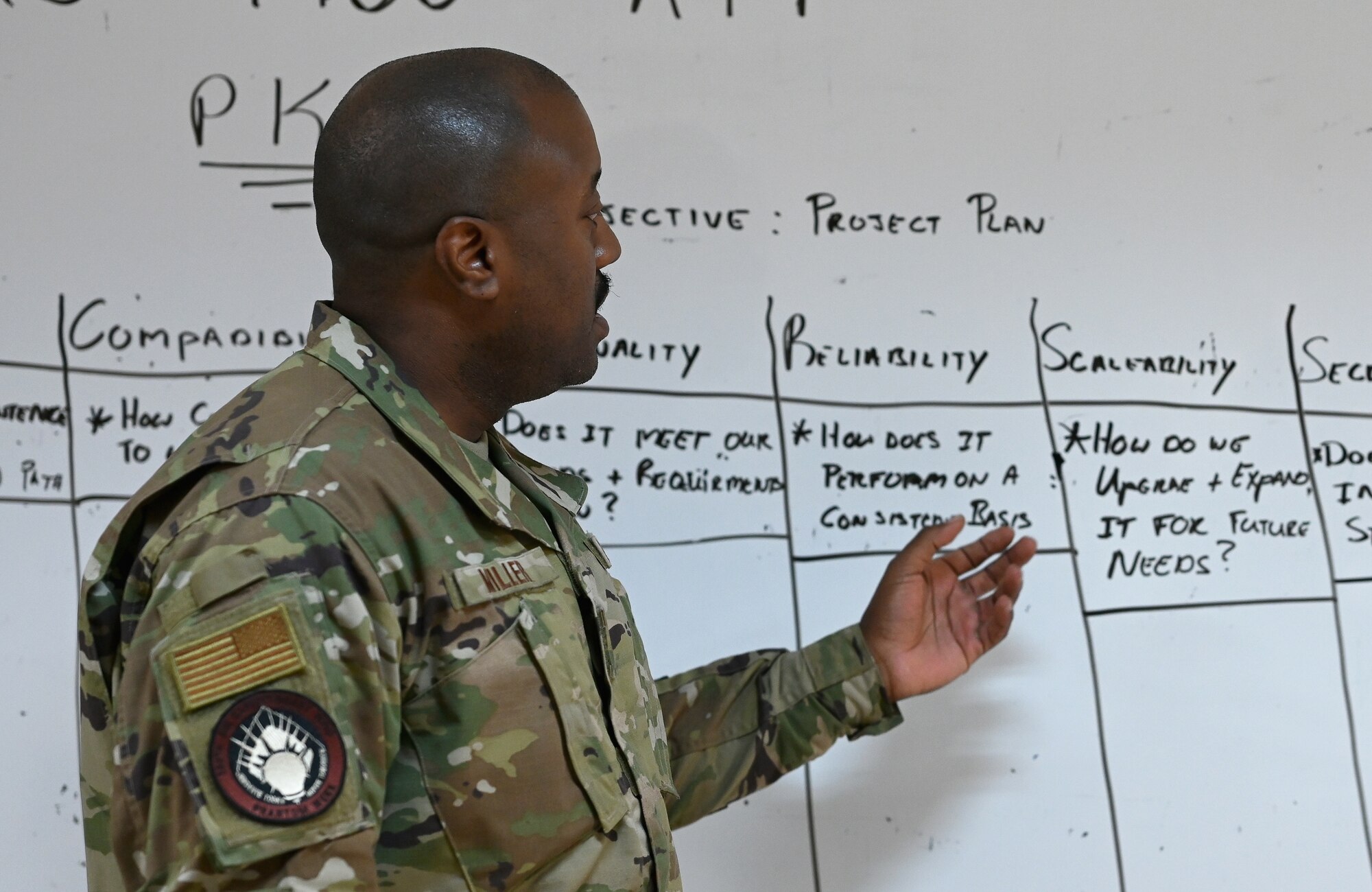 A photo of a man briefing in front of a white board.