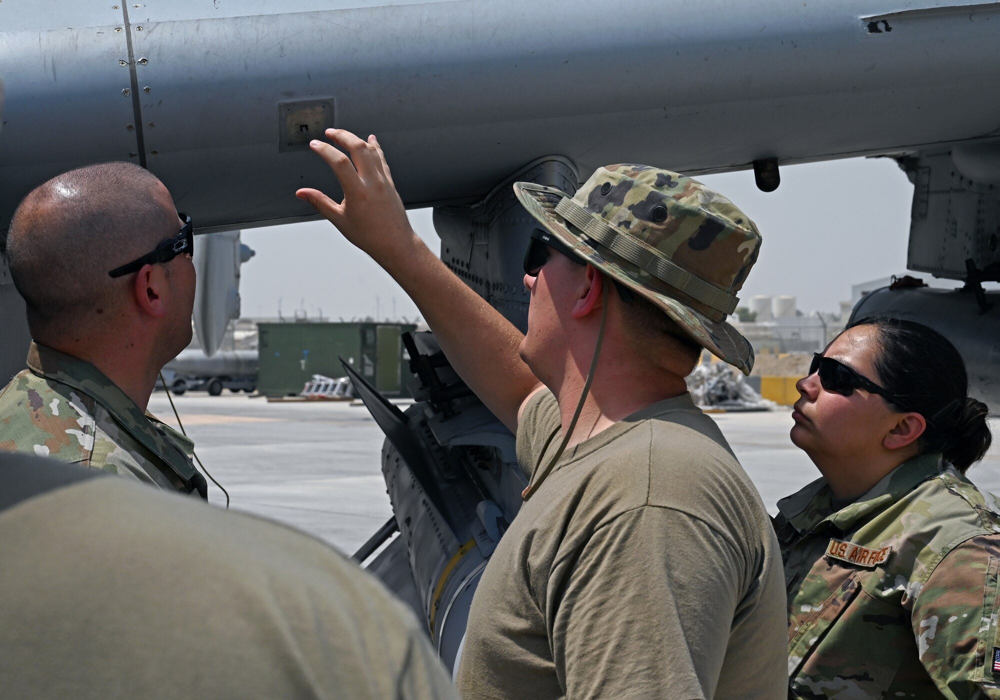 A photo of three people looking at an aircraft.