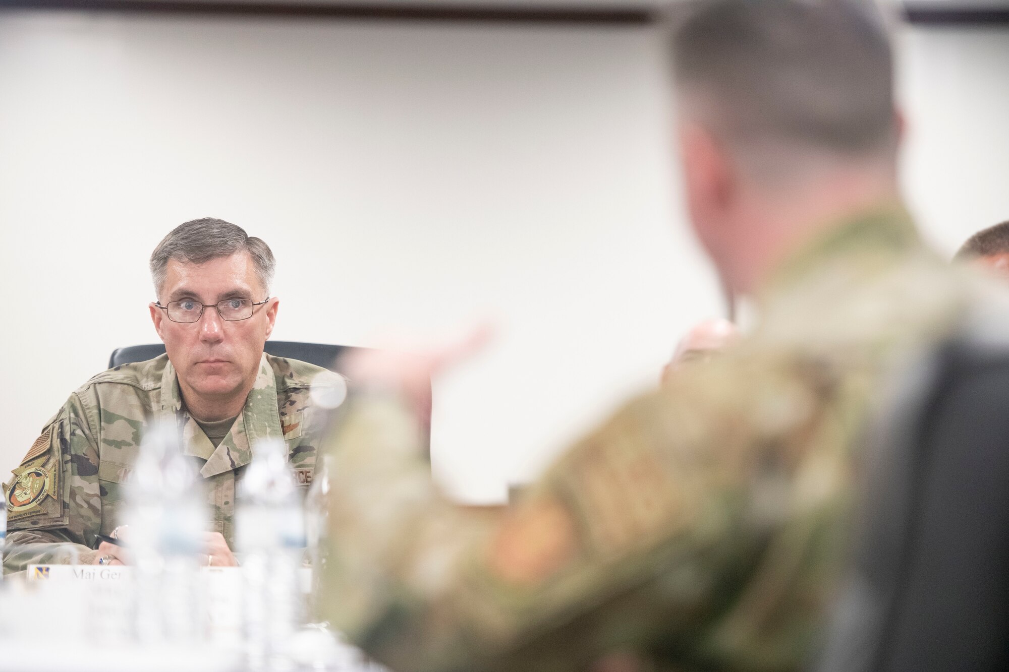 Two soldiers converse at a conference table