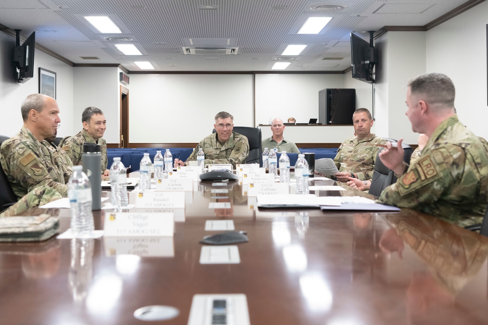 six soldiers talk at a conference table
