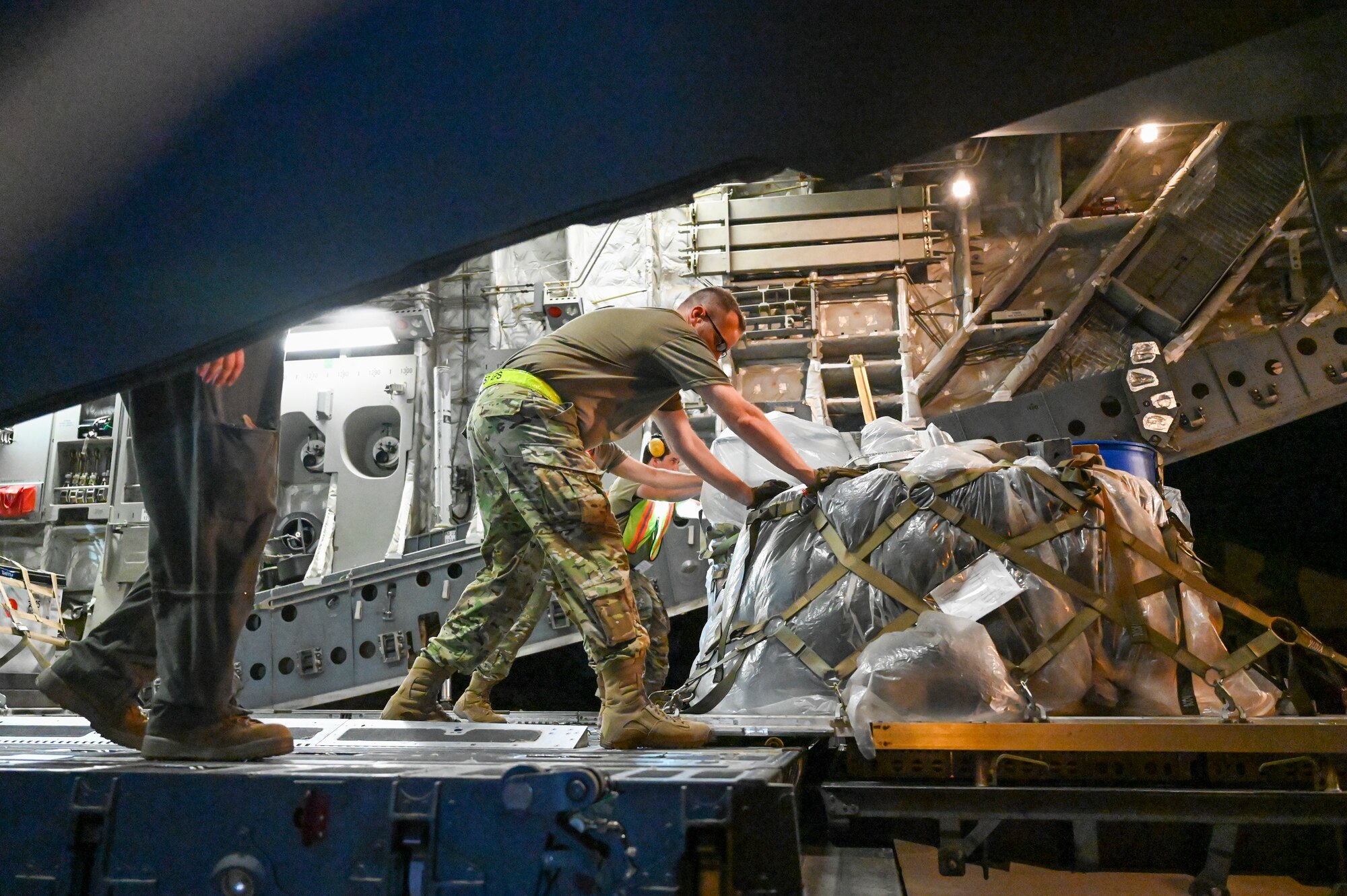 Photo of individuals unwrapping a pallet of unidentified goods.