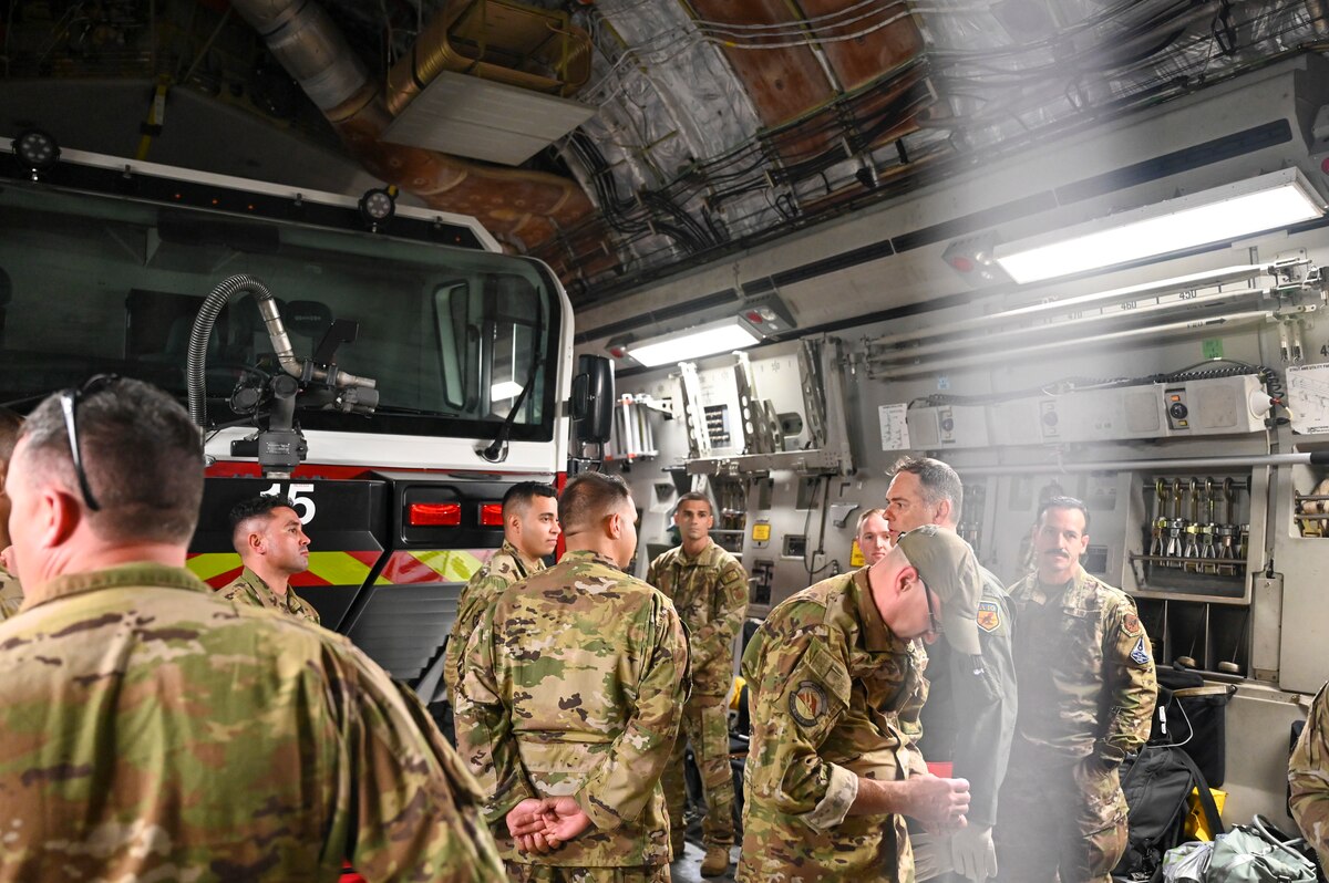 Photo of a group of people standing in front of a firetruck.