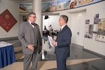 two gentlemen talk in an auditorium