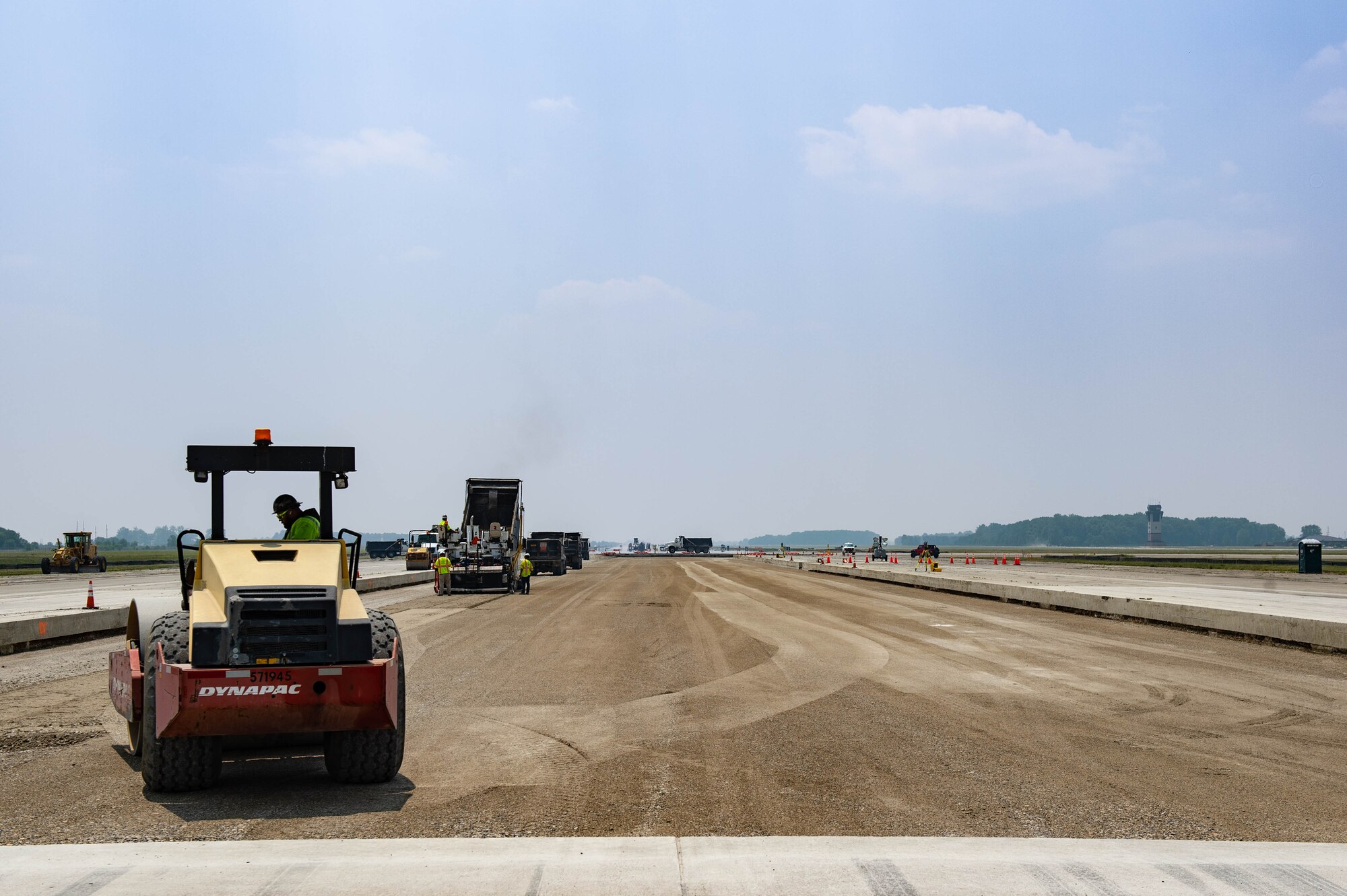 Construction vehicles install base materials on a stretch of runway at Grissom Air Reserve Base, Ind. on June 9, 2023. Flying operations have temporarily moved to other locations while construction crews are hard at work resurfacing the entire length of the runway and updating the lighting systems. (U.S. Air Force Photo by Airman Elise Faurote)