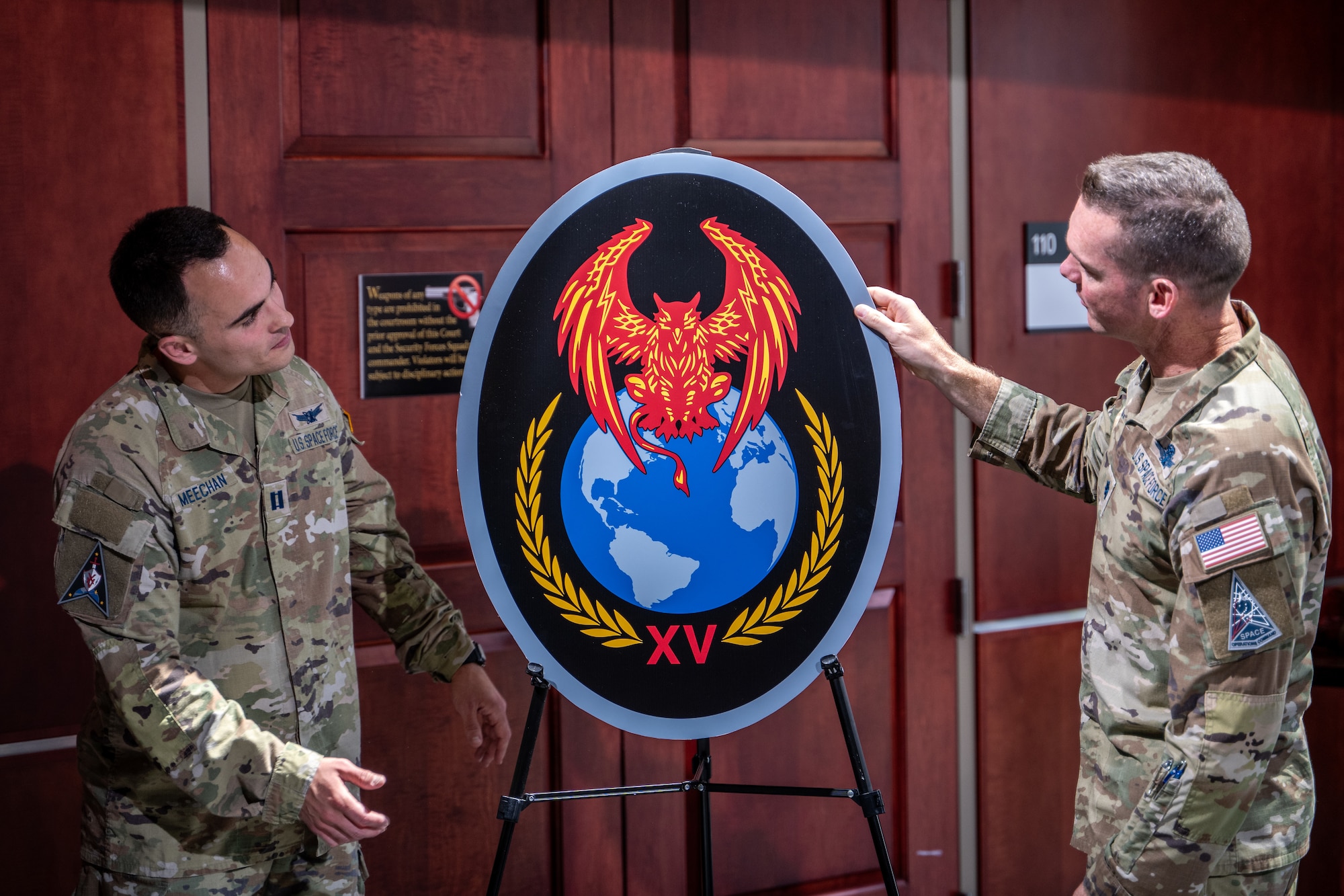 Two men in uniform unveil an emblem