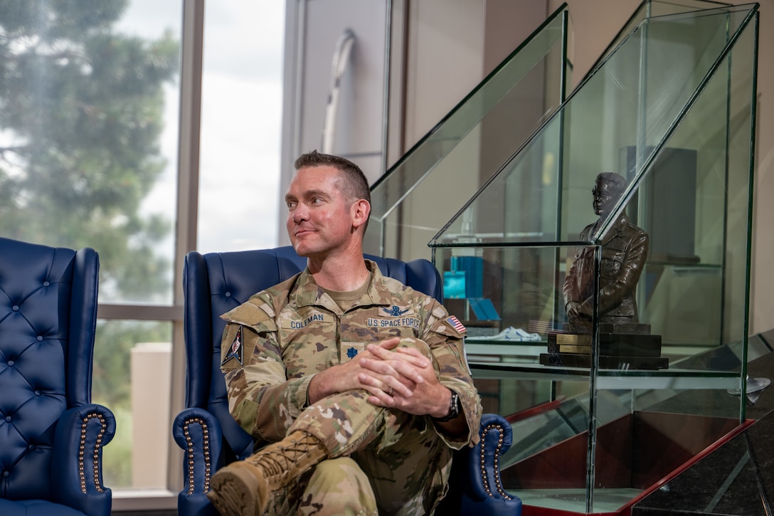 Man in uniform sits in a chair with his legs crossed