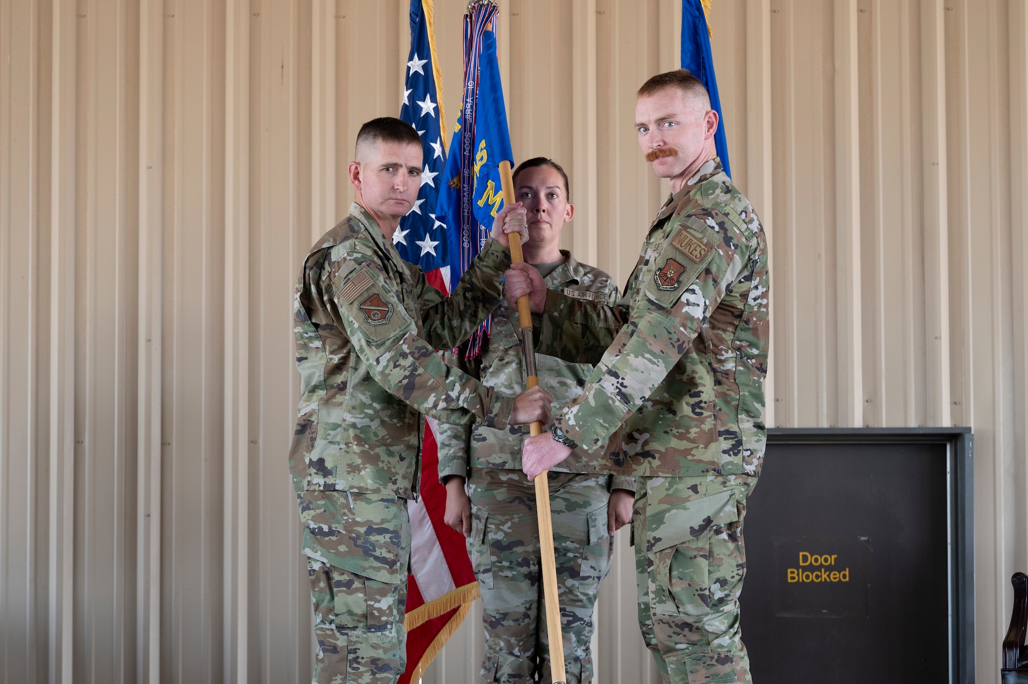 A man hands a man a guidon.