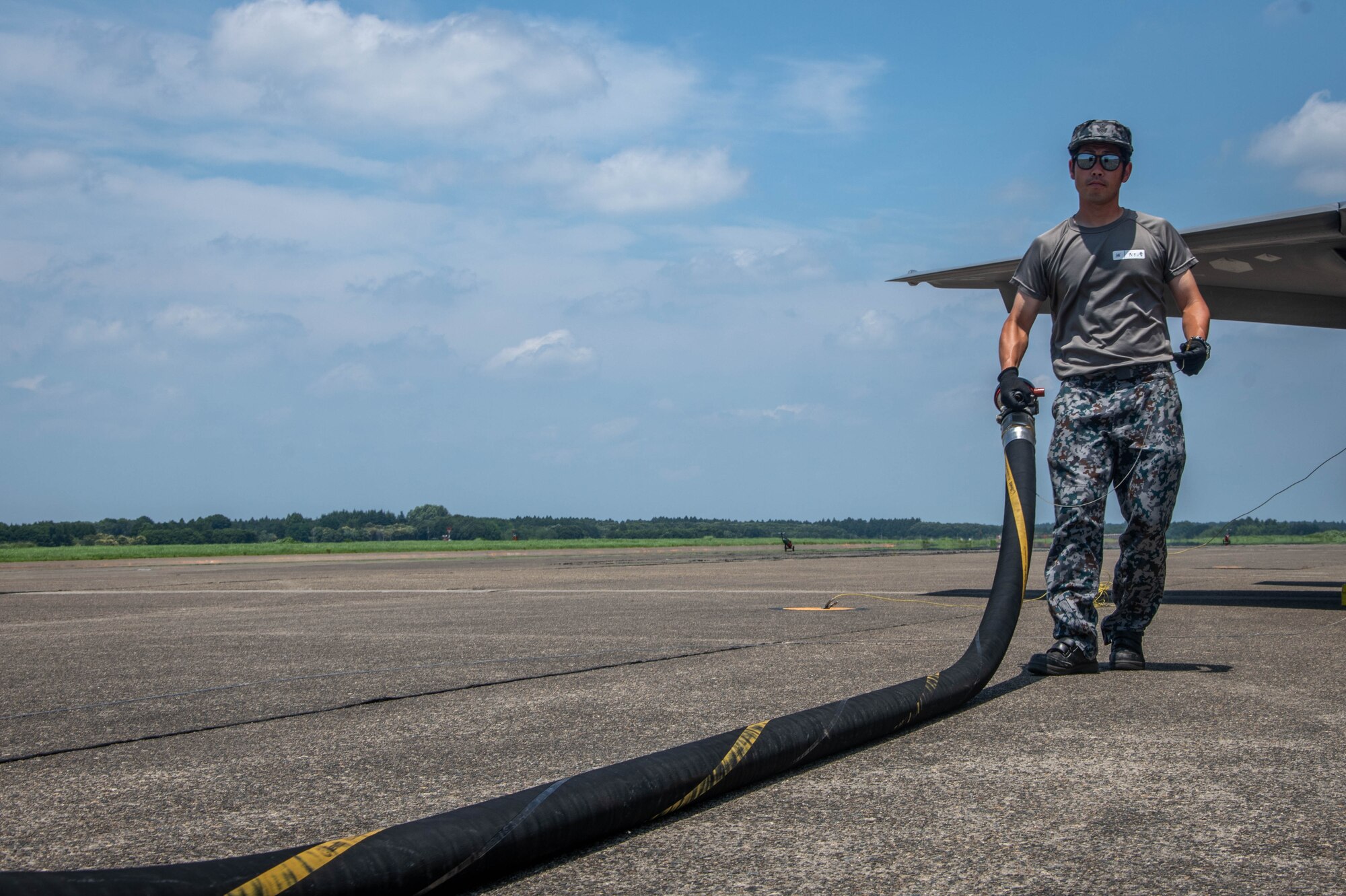A JASDF holds a hose after a hot-pit refuel.
