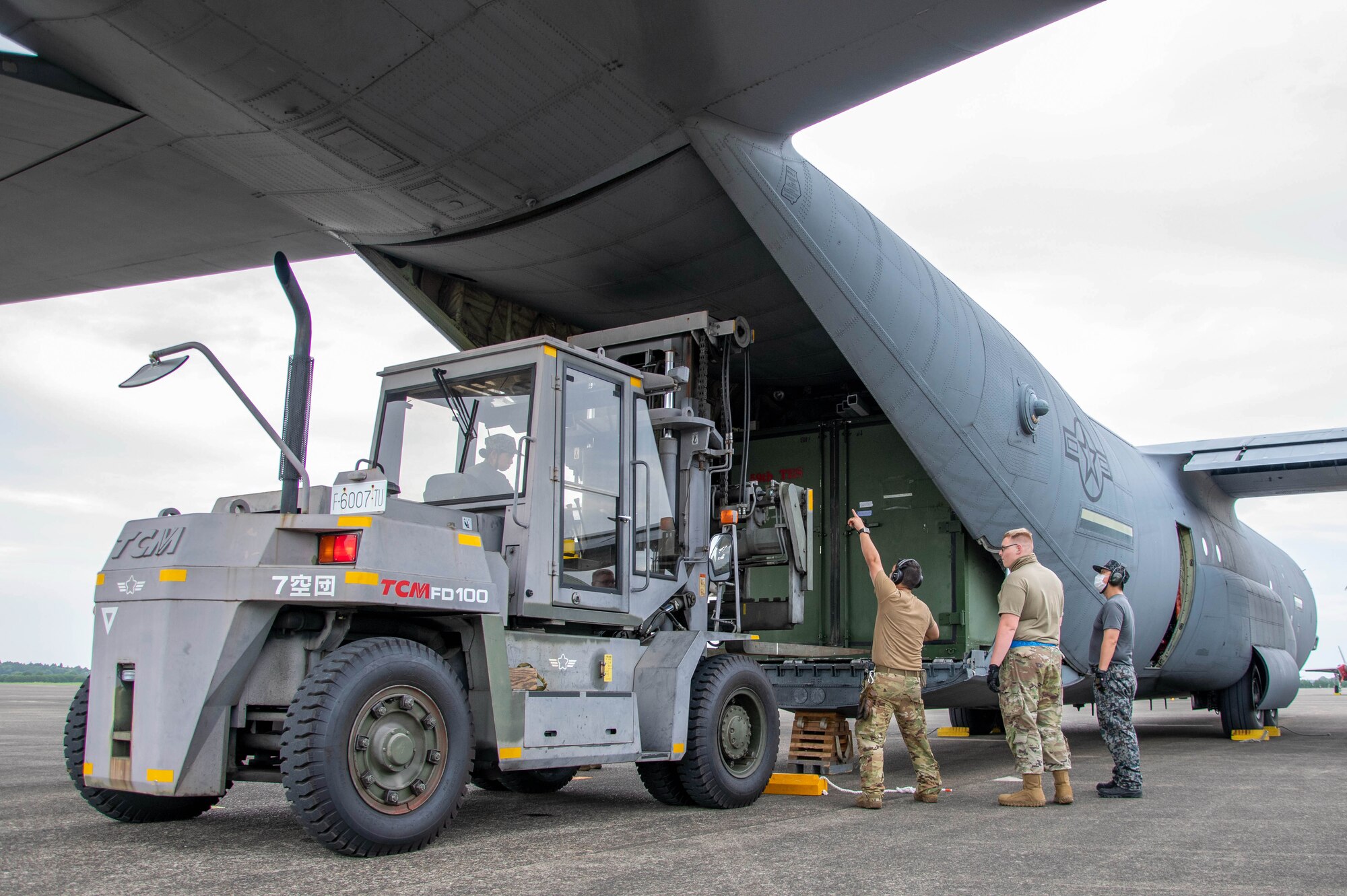 Airmen and JASDF unload cargo from an aircraft.