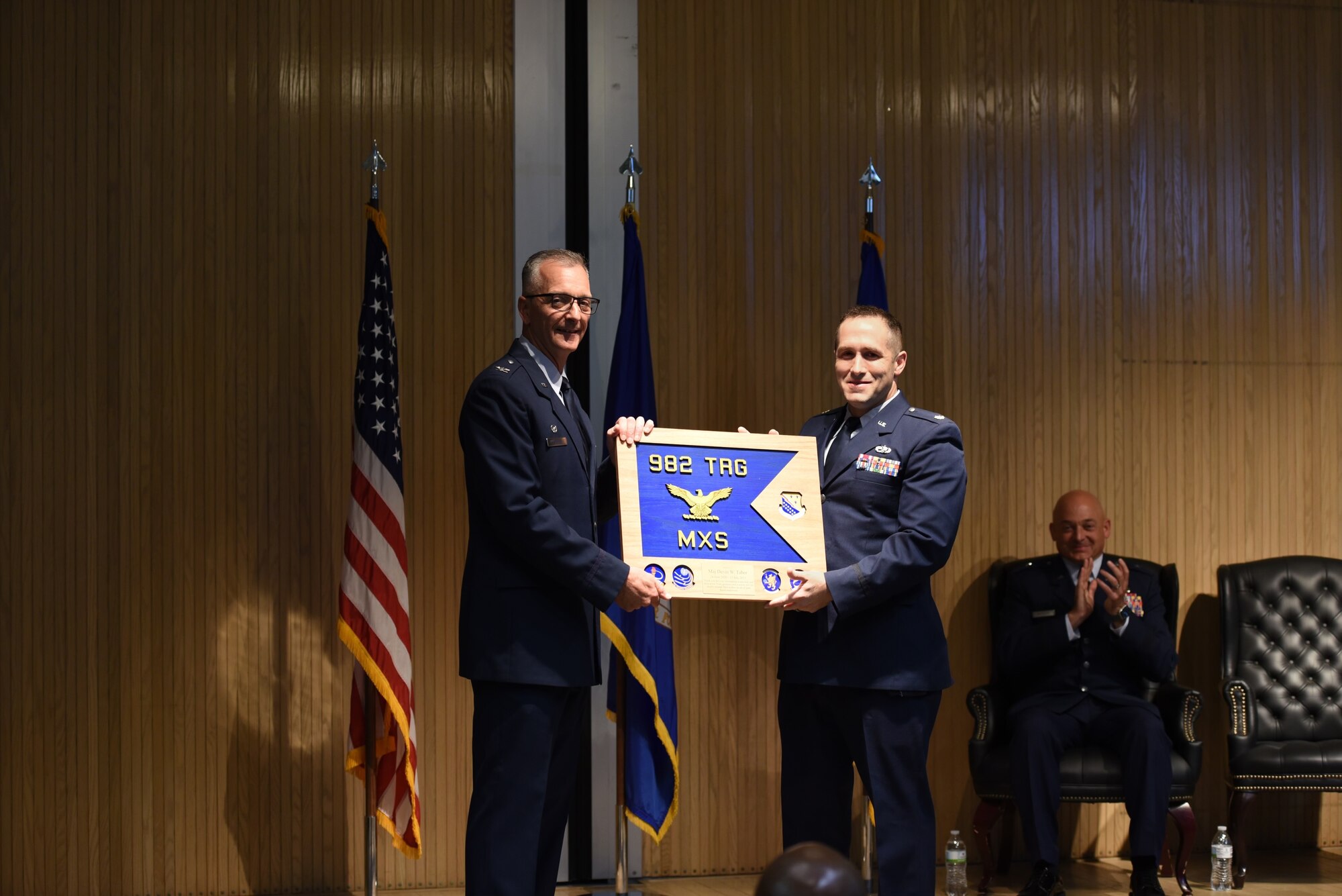 U.S. Air Force Col. Terry Koester presents Maj. Devin Taber with a plaque simulating the guidon for the now inactivated 982d MXS.