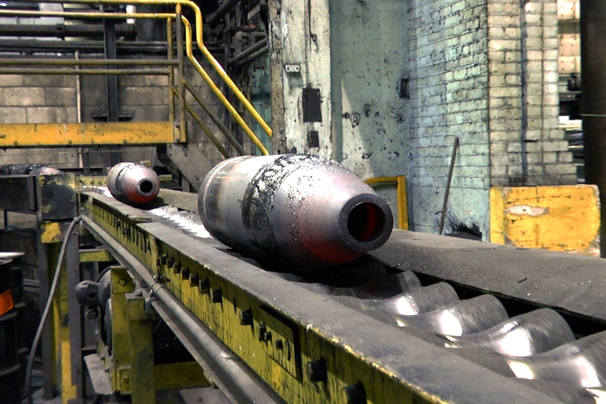 Two metal pieces of equipment sit on an assembly line shelf with rollers.