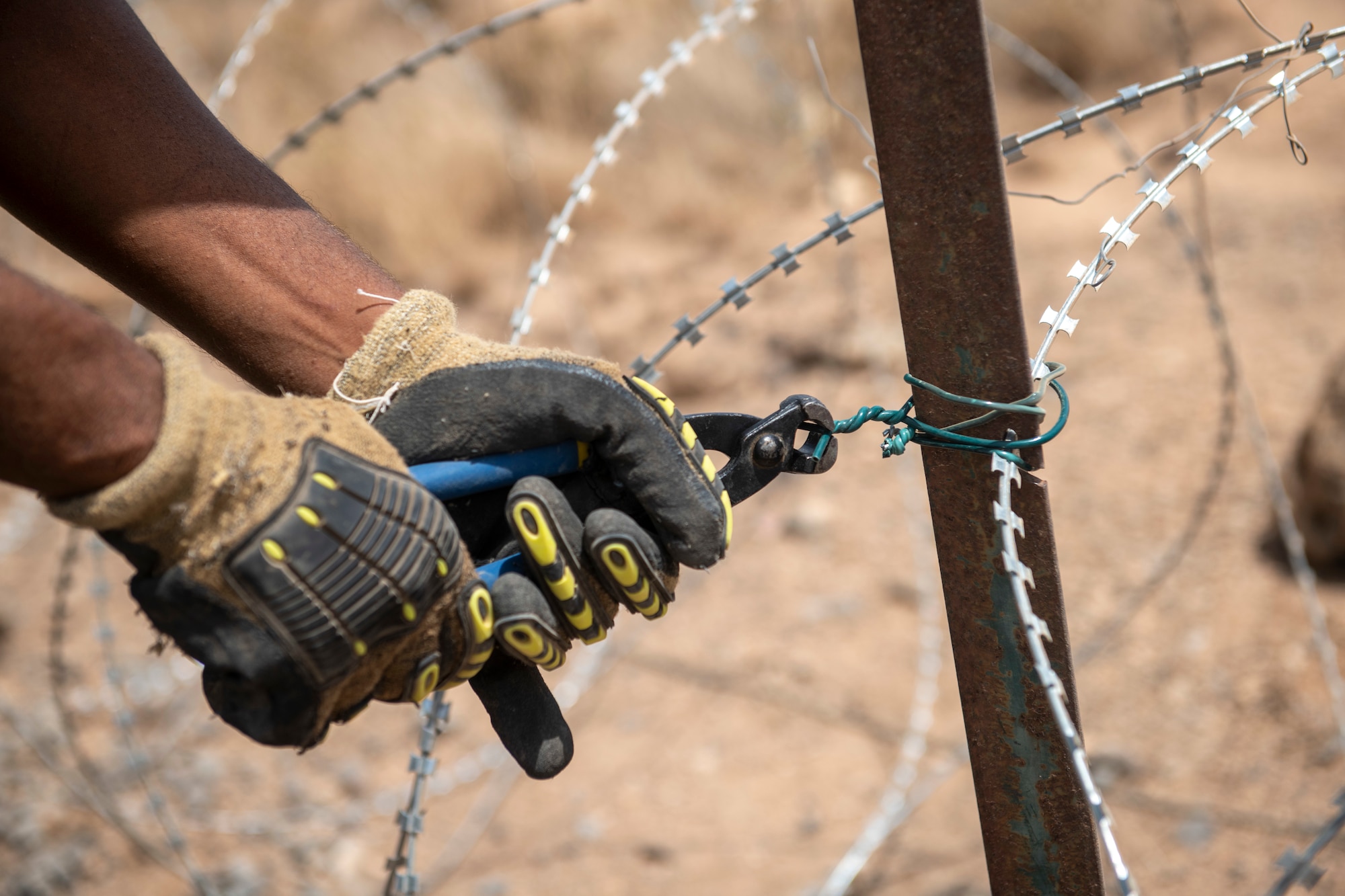 Photo of a workman's hands using a tool to twist wire