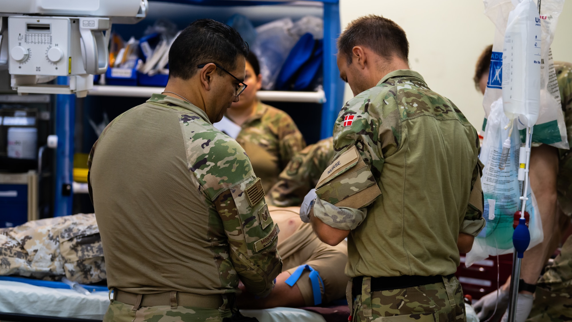 U.S. Air Force Airmen from the 386th Expeditionary Medical Squadron, and a member of the Royal Danish Air Force, tend to the wounds of a victim from a simulated aircraft crash during a medical response exercise at Ali Al Salem Air Base, Kuwait, July 17, 2023. This exercise tested the emergency response systems of U.S. and coalition forces, which allowed for a better understanding of how they can communicate and operate together in the event of a real-world emergency. (U.S. Air Force photo by Staff Sgt. Kevin Long)