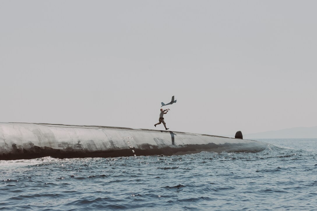 A Marine launches an unmanned aircraft from the top of a submarine.