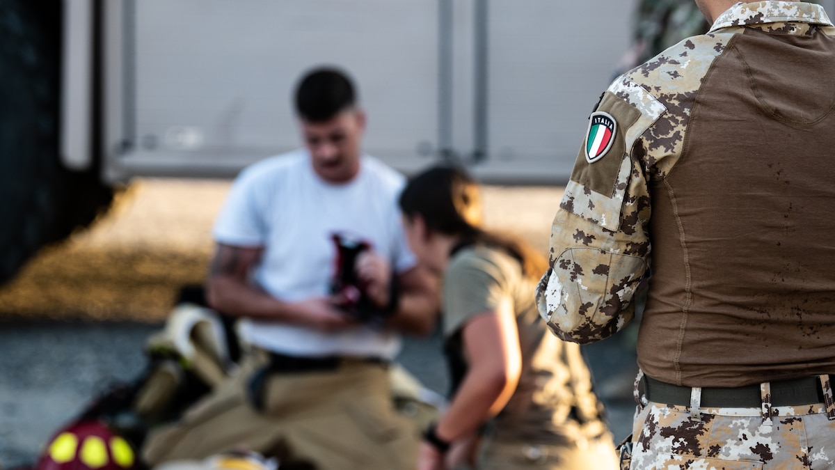 A member of the Italian Air Force observes as U.S. Air Force fire protection Airmen from the 386th Expeditionary Civil Engineer Squadron perform first aid on a victim from a simulated aircraft crash during a medical response exercise at Ali Al Salem Air Base, Kuwait, July 17, 2023. This exercise tested the emergency response systems of U.S. and coalition forces, which allowed for a better understanding of how they can communicate and operate together in the event of a real-world emergency. (U.S. Air Force photo by Staff Sgt. Kevin Long)