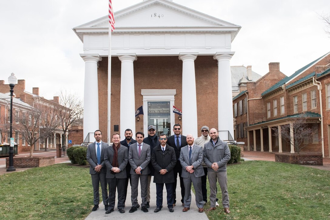 Group of men standing in front of historic court house building.