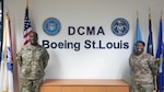 Male and female soldiers wear Army uniforms and stand near flags