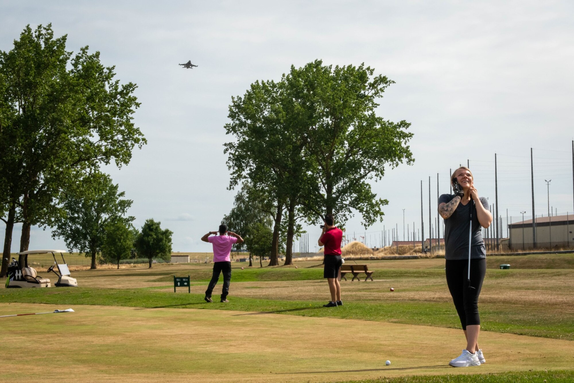 Participants of a golf tournament watch a U.S. Air Force F-16 Flying Falcon as it takes off .