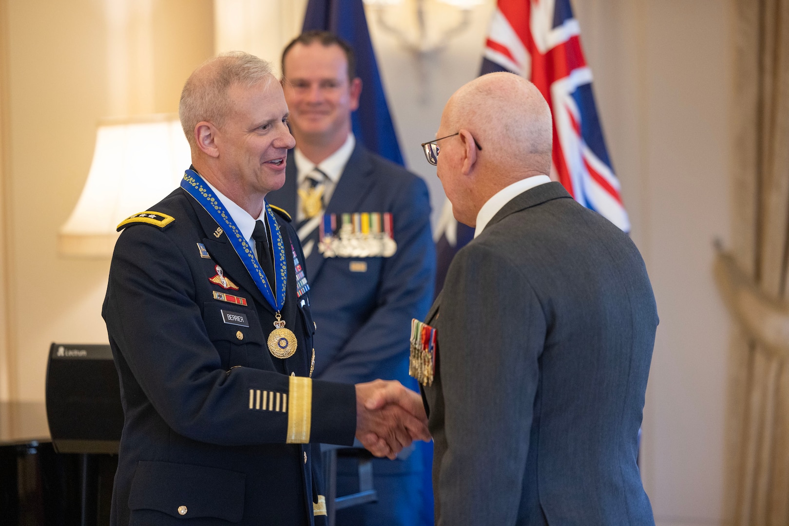 Two men greeting each other with a third on-looking in the background.