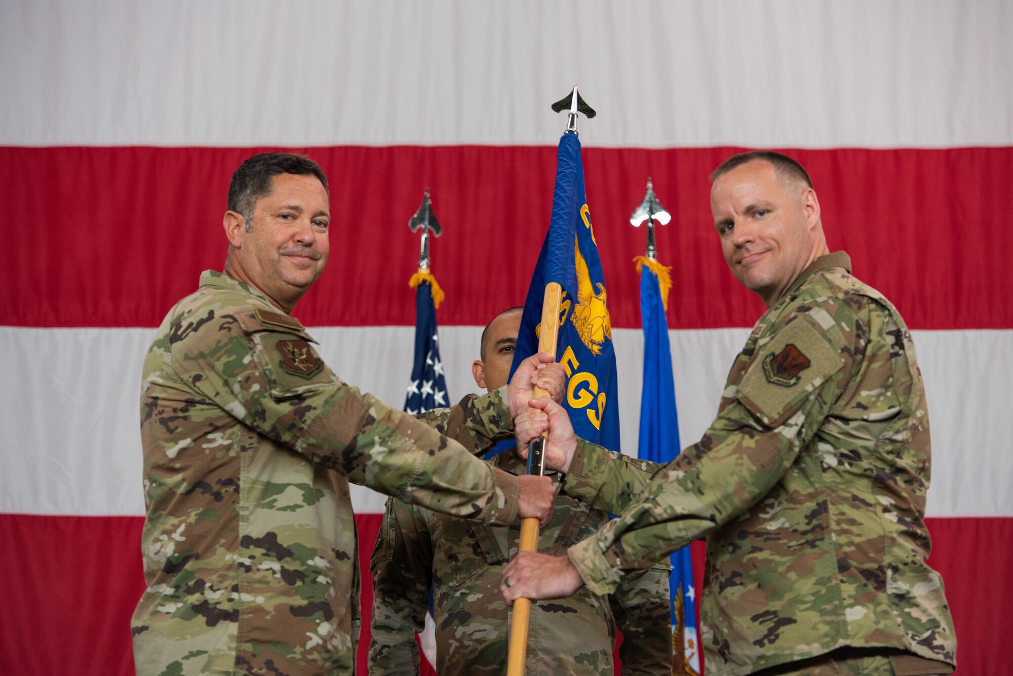 A photo of two people in military uniform holding a flag in between themselves.