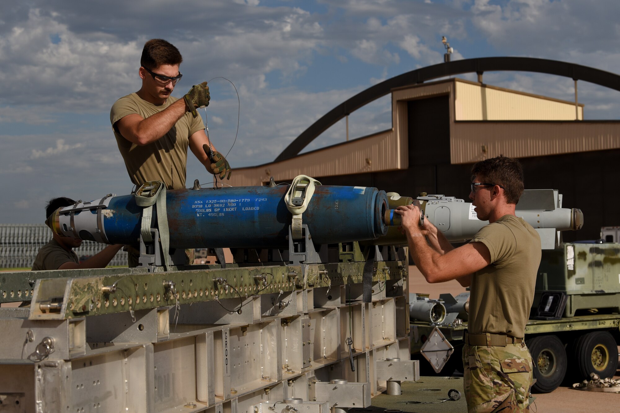 U.S. Air Force  Senior Airmen Tyler Coburn and Easton Gragg , 7th Munitions Squadron munitions technicians, thread a power cable through an inert Joint Direct Attack Munition during  the Lone Star Challenge at Dyess Air Force Base, Texas, July 13, 2023. Two  teams competed in various components which tested the abilities of Airmen from multiple squadrons in building, preparing and loading JDAMs into the B-1B Lancer. The event was designed to exercise real-world actions the 7th Bomb Wing would do if called for no notice missions.   (U.S. Air Force photo by Senior Airman Sophia Robello)