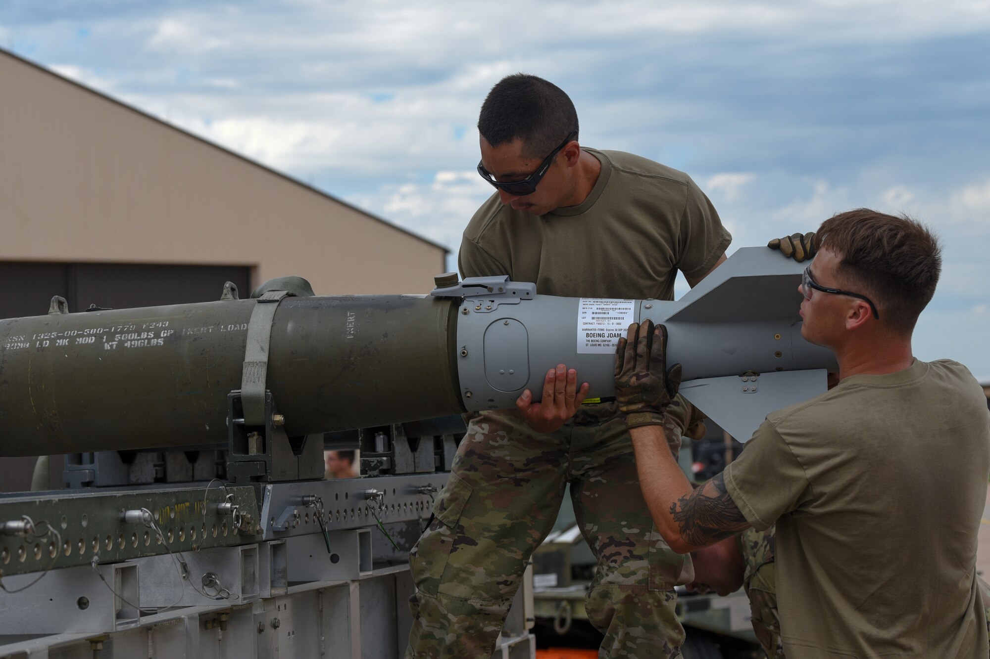 Airman 1st Class Nicholas Ochoa and Senior Airman Logan Fincannon, 7th Munitions Squadron munitions technicians, position a tail assembly on an inert Joint Direct Attack Munition during the Lone Star Challenge at Dyess Air Force Base, Texas, July 13, 2023. Two teams competed in various components which tested the abilities of Airmen from multiple squadrons in building, preparing and loading JDAMs into the B-1B Lancer. The event was designed to exercise real-world actions the 7th Bomb Wing would do if called for no notice missions. (U.S. Air Force photo by Senior Airman Sophia Robello)