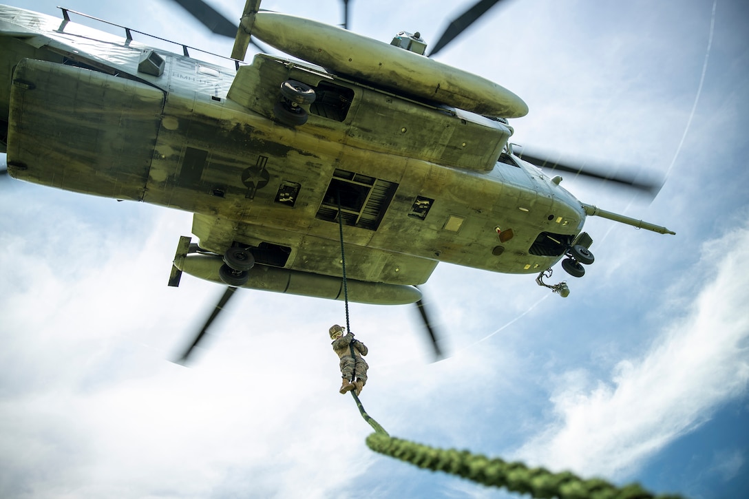 A Marine fast-ropes from a military helicopter.