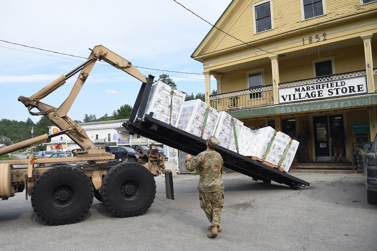 A soldier guides a truck delivering water.