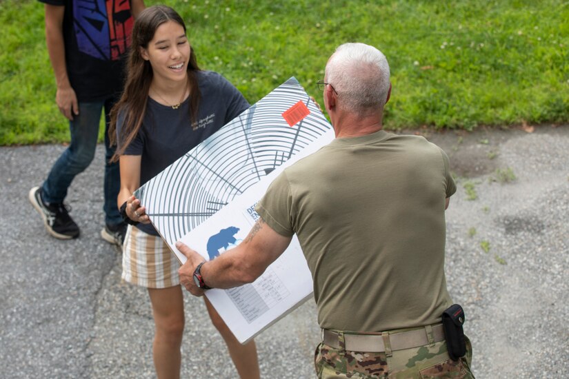 A soldier gives a box to a young girl.