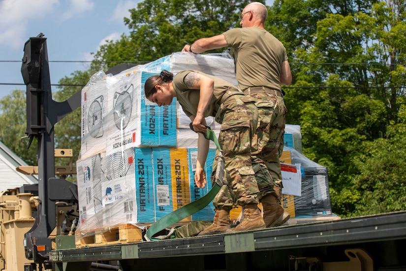Soldiers unload supplies from a truck.