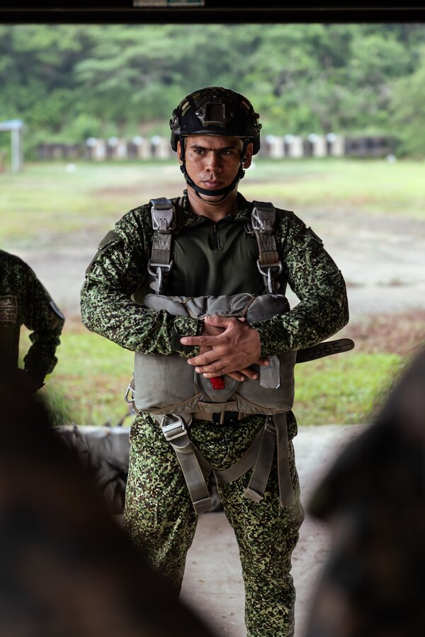 A Colombian reconnaissance Marine stands with his parachute equipment during low level static line training for UNITAS LXIV at Cartagena, Colombia, July 17, 2023. During UNITAS, reconnaissance and special operation force Marines from partner and allied nations conducted multilateral special operations training consisting of room clearing, visit board search and seizure, jungle patrolling, low level static line jumping, small arms, and helicopter rope suspension tactics. UNITAS, hosted by Colombia this year, is the world’s longest-running annual multinational maritime exercise that focuses on enhancing interoperability among multiple nations and joint forces during littoral and amphibious operations in order to build on existing regional partnerships and create new enduring relationships that promote peace, stability, and prosperity in the U.S. Southern Command’s area of responsibility. (U.S. Marine Corps photo by Sgt. Colton K. Garrett)