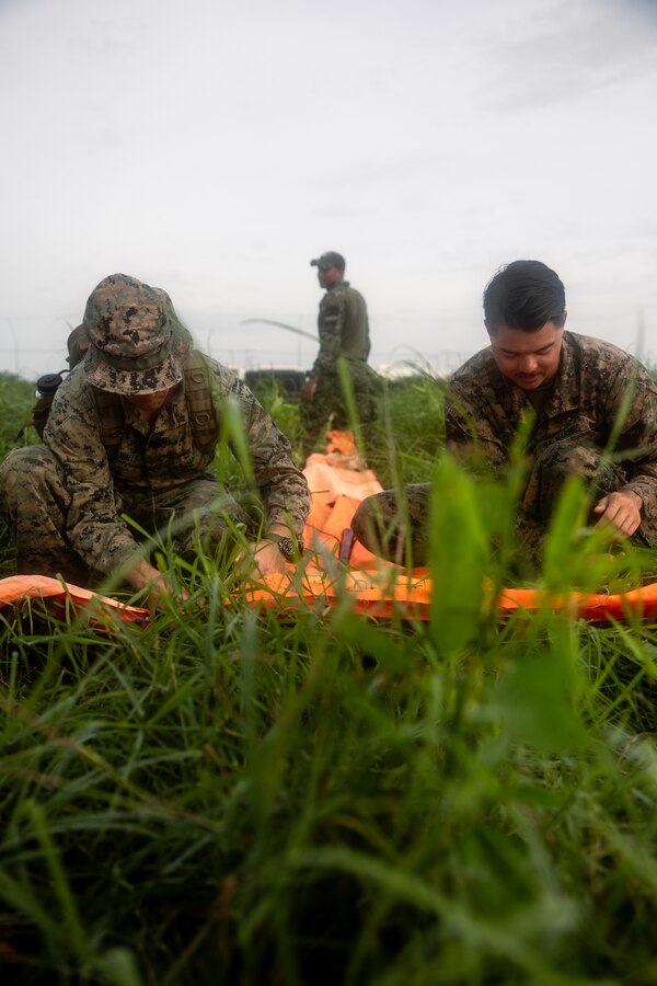 Two U.S. Marines with 4th reconnaissance Battalion, 4th Marine Division, assemble a drop zone marker during low level static line training for UNITAS LXIV at Cartagena, Colombia, July 18, 2023. During UNITAS, reconnaissance and special operation force Marines from partner and allied nations conducted multilateral special operations training consisting of room clearing, visit board search and seizure, jungle patrolling, low level static line jumping, small arms, and helicopter rope suspension tactics. UNITAS, hosted by Colombia this year, is the world’s longest-running annual multinational maritime exercise that focuses on enhancing interoperability among multiple nations and joint forces during littoral and amphibious operations in order to build on existing regional partnerships and create new enduring relationships that promote peace, stability, and prosperity in the U.S. Southern Command’s area of responsibility. (U.S. Marine Corps photo by Sgt. Colton K. Garrett)