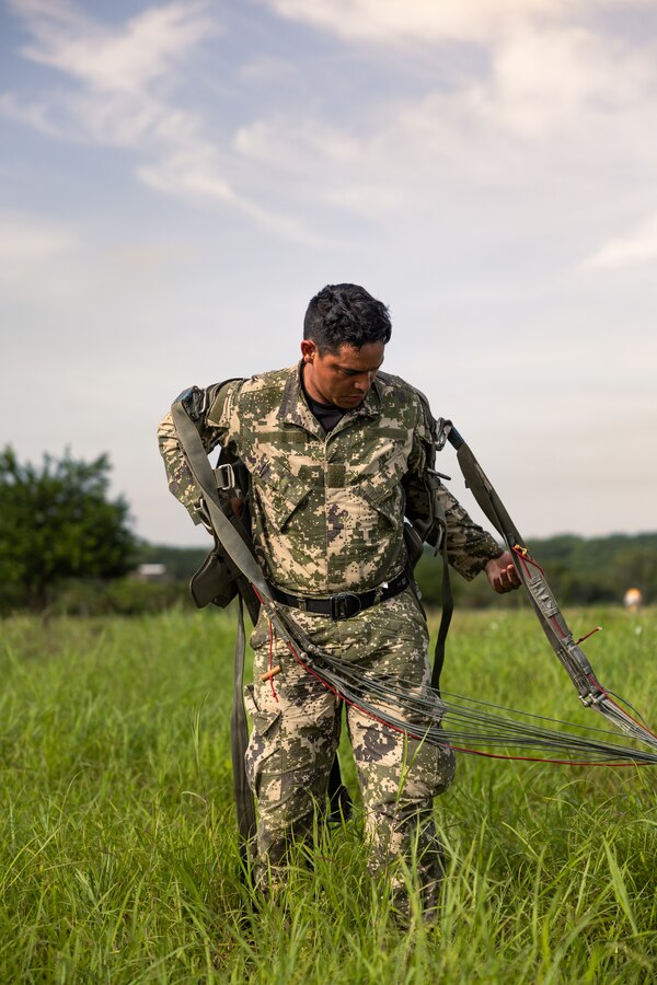 A Paraguayan reconnaissance Marine takes off his parachute harness after conducting a low level static line jump during UNITAS LXIV at Cartagena, Colombia, July 18, 2023. During UNITAS, reconnaissance and special operation force Marines from partner and allied nations conducted multilateral special operations training consisting of room clearing, visit board search and seizure, jungle patrolling, low level static line jumping, small arms, and helicopter rope suspension tactics. UNITAS, hosted by Colombia this year, is the world’s longest-running annual multinational maritime exercise that focuses on enhancing interoperability among multiple nations and joint forces during littoral and amphibious operations in order to build on existing regional partnerships and create new enduring relationships that promote peace, stability, and prosperity in the U.S. Southern Command’s area of responsibility. (U.S. Marine Corps photo by Sgt. Colton K. Garrett)