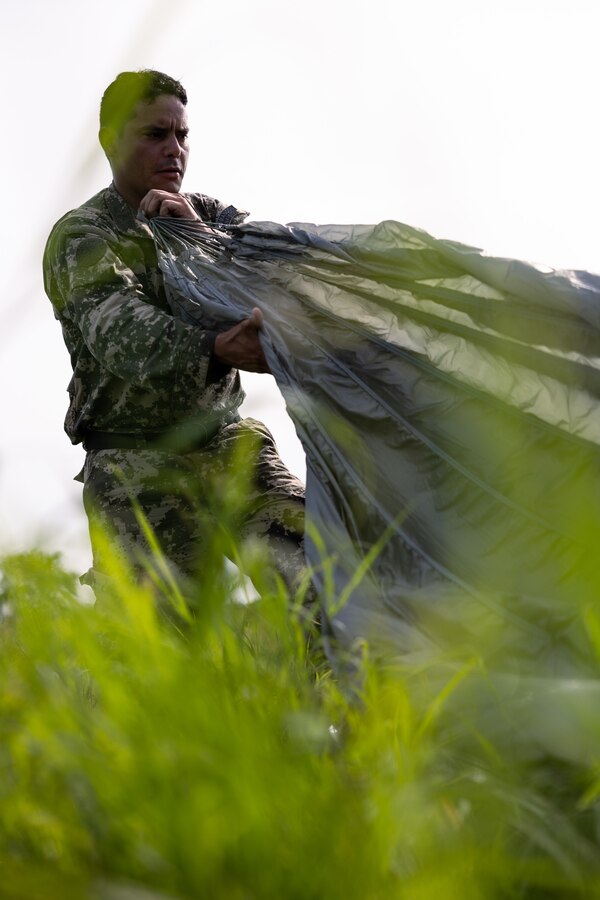 A Paraguayan reconnaissance Marine recovers his parachute after conducting a low level static line jump during UNITAS LXIV at Cartagena, Colombia, July 18, 2023. During UNITAS, reconnaissance and special operation force Marines from partner and allied nations conducted multilateral special operations training consisting of room clearing, visit board search and seizure, jungle patrolling, low level static line jumping, small arms, and helicopter rope suspension tactics. UNITAS, hosted by Colombia this year, is the world’s longest-running annual multinational maritime exercise that focuses on enhancing interoperability among multiple nations and joint forces during littoral and amphibious operations in order to build on existing regional partnerships and create new enduring relationships that promote peace, stability, and prosperity in the U.S. Southern Command’s area of responsibility. (U.S. Marine Corps photo by Sgt. Colton K. Garrett)