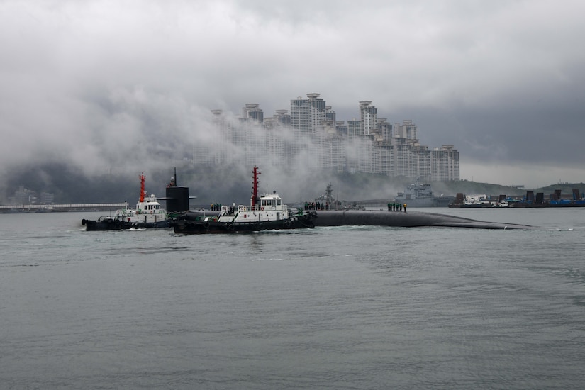 A submarine pulls into port in a large city.