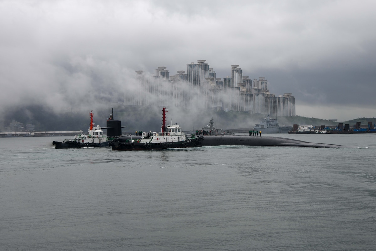 A submarine pulls into port in a large city.