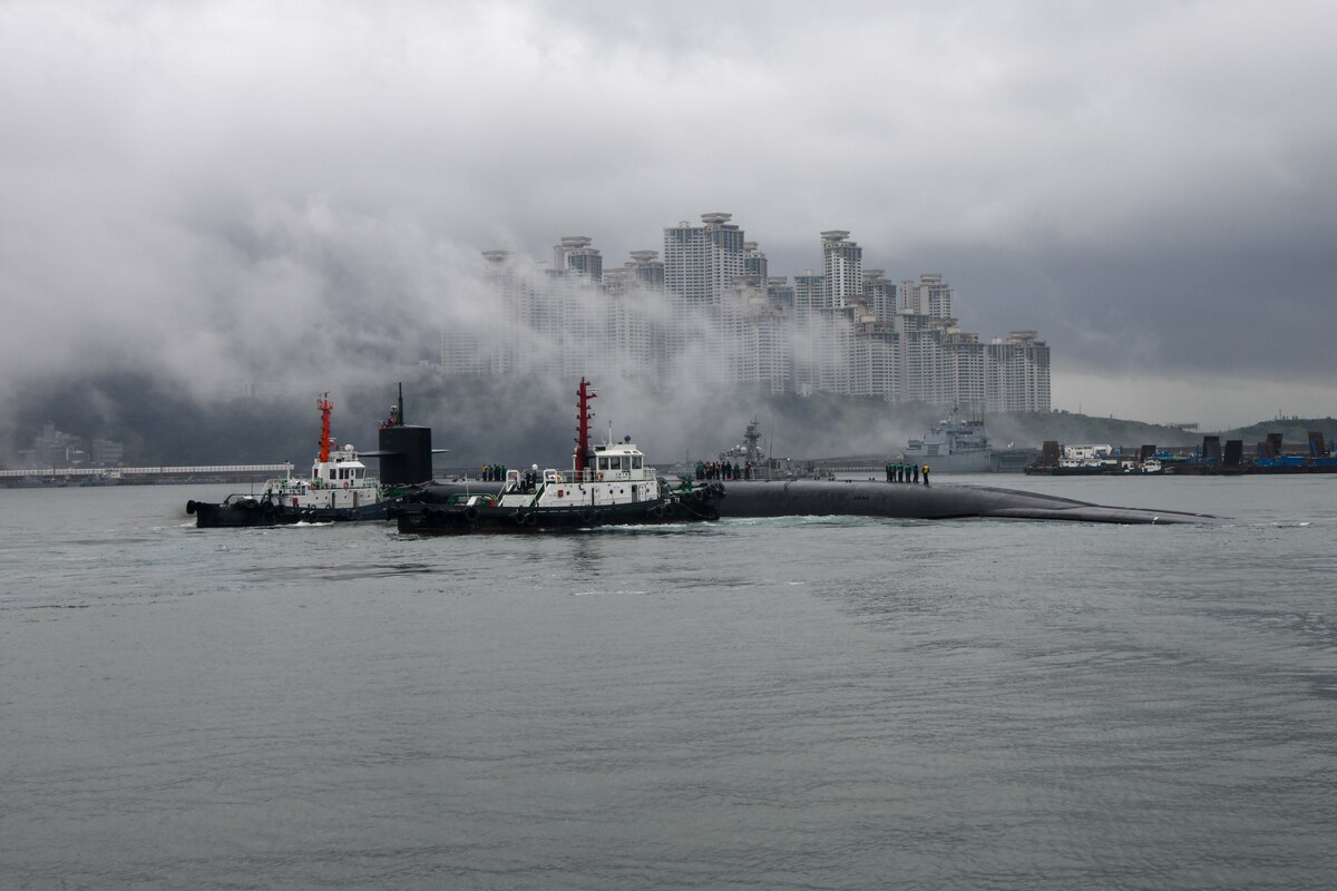 A submarine pulls into port in a large city.