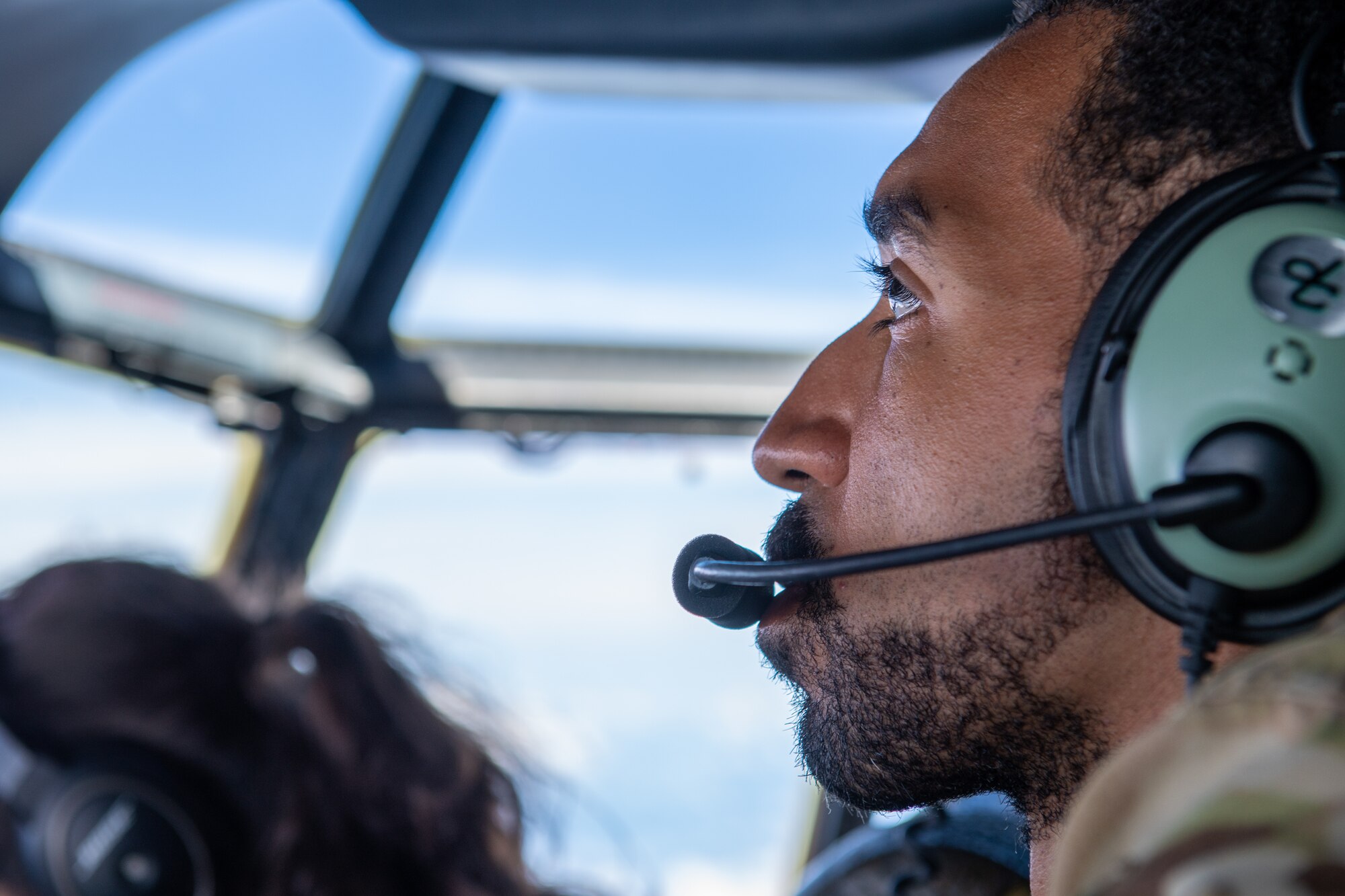 An Airman monitors the overhead panel in the flight deck of a C-130J