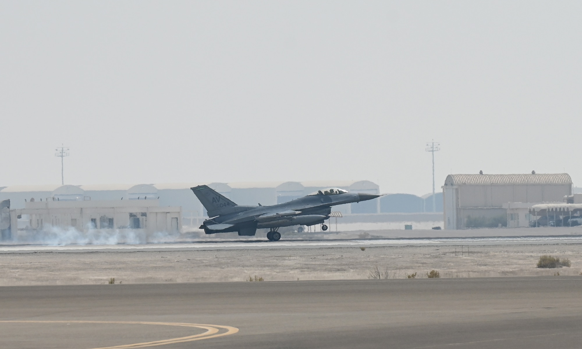 A photo of a jet landing on a flightline.