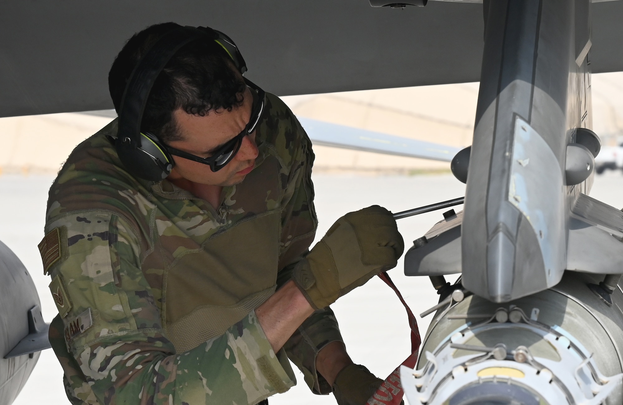 A photo of a man replacing a pin on a jet.