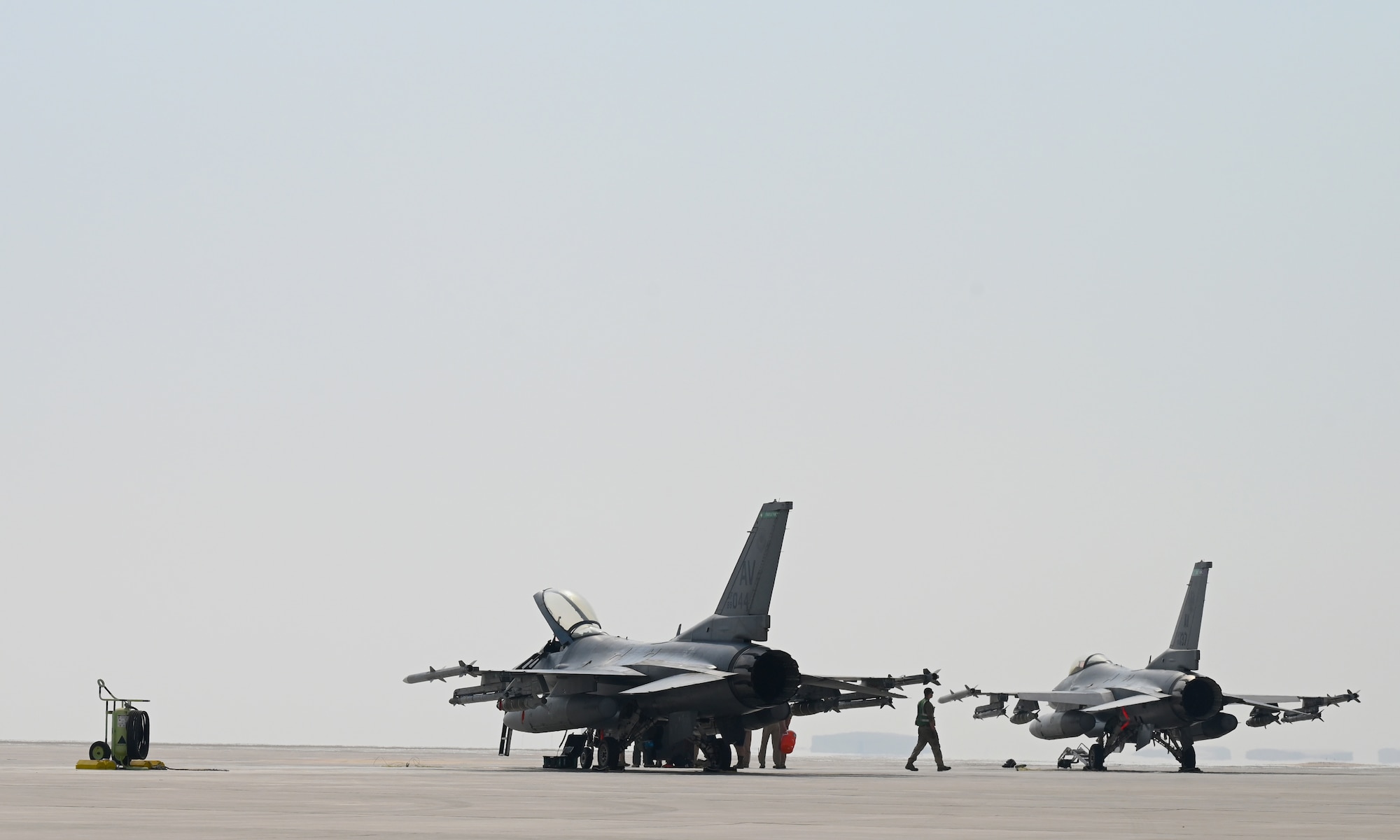 A photo of two jets sitting on the flightline.