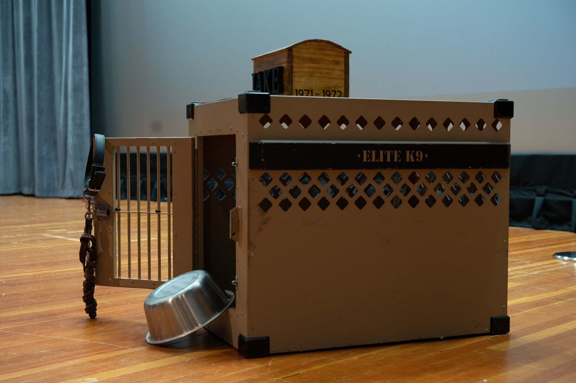 A vacant K-9 kennel sits on stage during Military Working Dog OX14 Jake’s memorial ceremony at Dover Air Force Base, Delaware, July 10, 2023. The 436th SFS held the memorial ceremony in hopes of providing closure to retired U.S. Air Force Staff Sgt. Mark Smoot, MWD Jake’s handler, during their deployment to Vietnam in 1971. (U.S. Air Force photo by Airman 1st Class Dieondiere Jefferies)