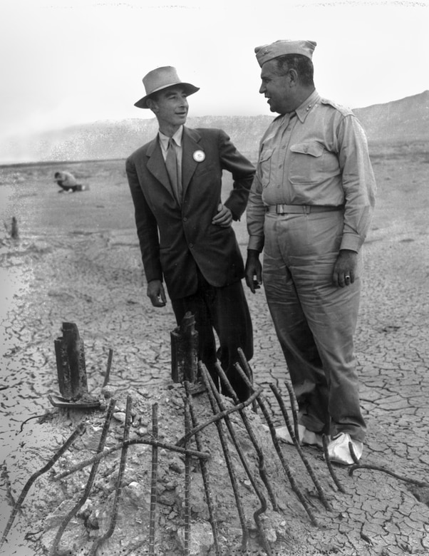 Two men talk outside on parched, desolate ground.