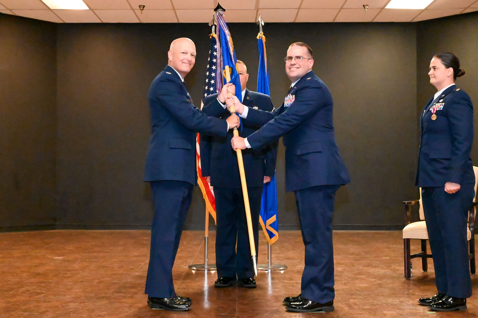 U.S. Air Force Col. Blaine Baker, 97th Air Mobility Wing commander, passes the 97th Comptroller Squadron (CPTS) guidon to Lt. Col. Jared Scherff, 97th CPTS commander, during a change of command ceremony at Altus Air Force Base (AFB), Oklahoma, June 23, 2023. The Wing Staff consists of more than one hundred personnel with a $1.2 million budget providing command and staff support for the nation's premiere Air Mobility Training Center. (U.S. Air Force photo by Senior Airman Kayla Christenson)