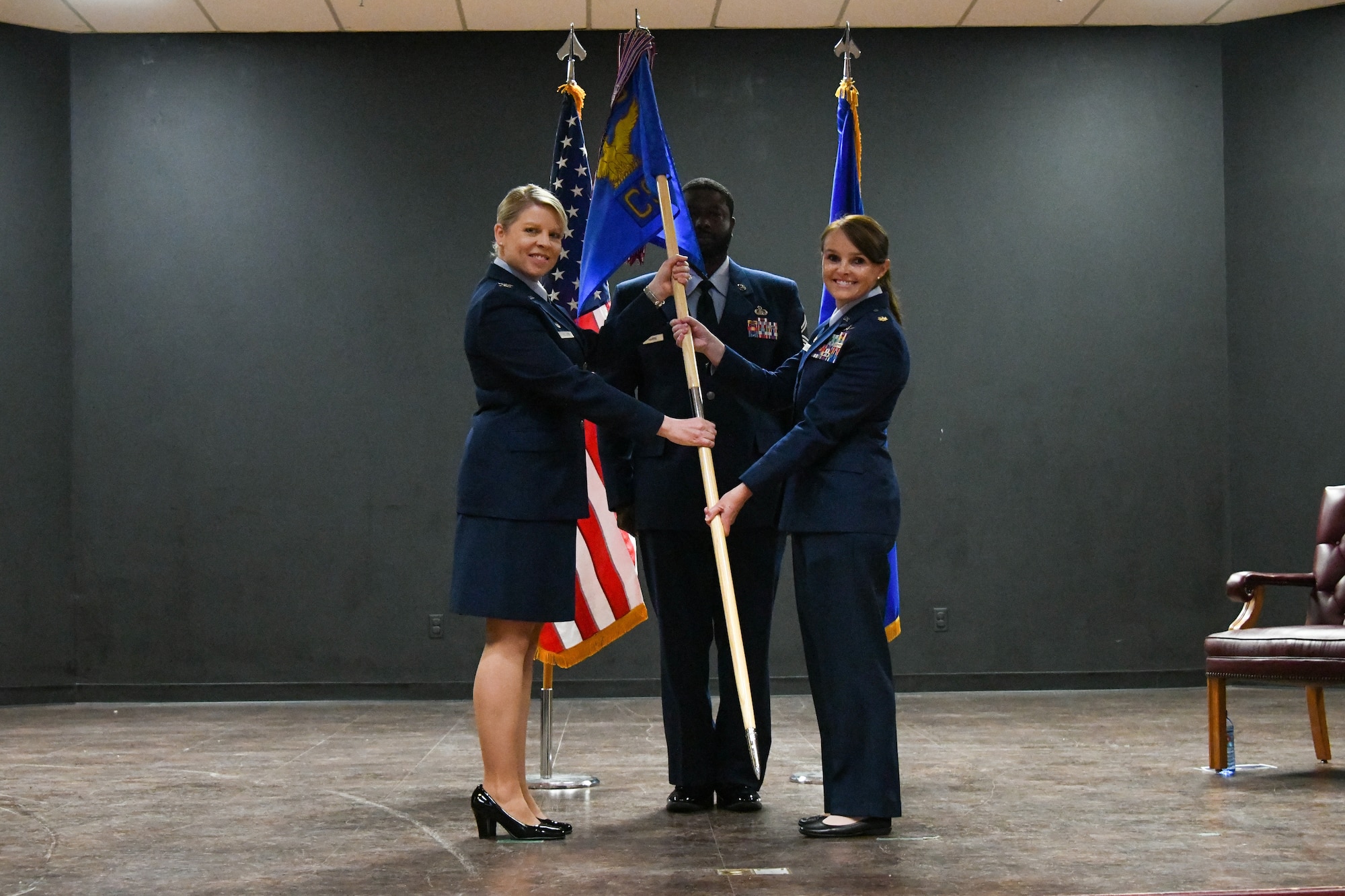U.S. Air Force Col. Tammy Hollister, 97th Mission Group commander, passes the 97th Communications Squadron (CS) guidon to Maj. Raine Ulrich, 97th CS commander, during a change of command ceremony at Altus Air Force Base (AFB), Oklahoma, June 23, 2023. The 97th CS is responsible for command, control, communications, and computer systems, operating and maintaining a $25 million network infrastructure and client support mission. (U.S. Air Force photo by Airman 1st Class Miyah Gray)