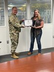 Col Aaron Heick, mobilization assistant to the Commander, Oklahoma City Air Logistics Complex presents Tonya Perkins with  the Commanders Excellence In Action award for developing an comprehensive book for the 551st CMXG commodities maintenance squadron. The book provides a high level process maps for every shop within the 551st.