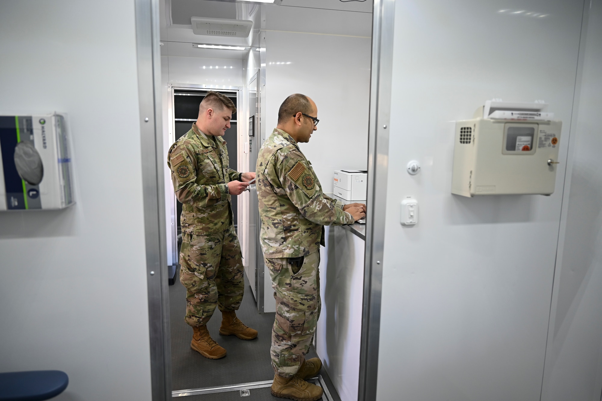 Two men stand in a trailer.