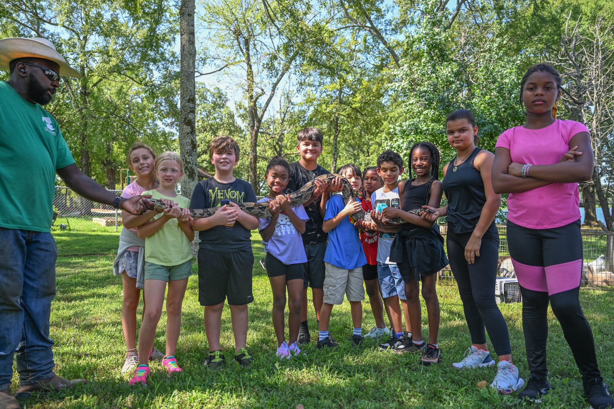A group of children pose for a photo holding a snake.