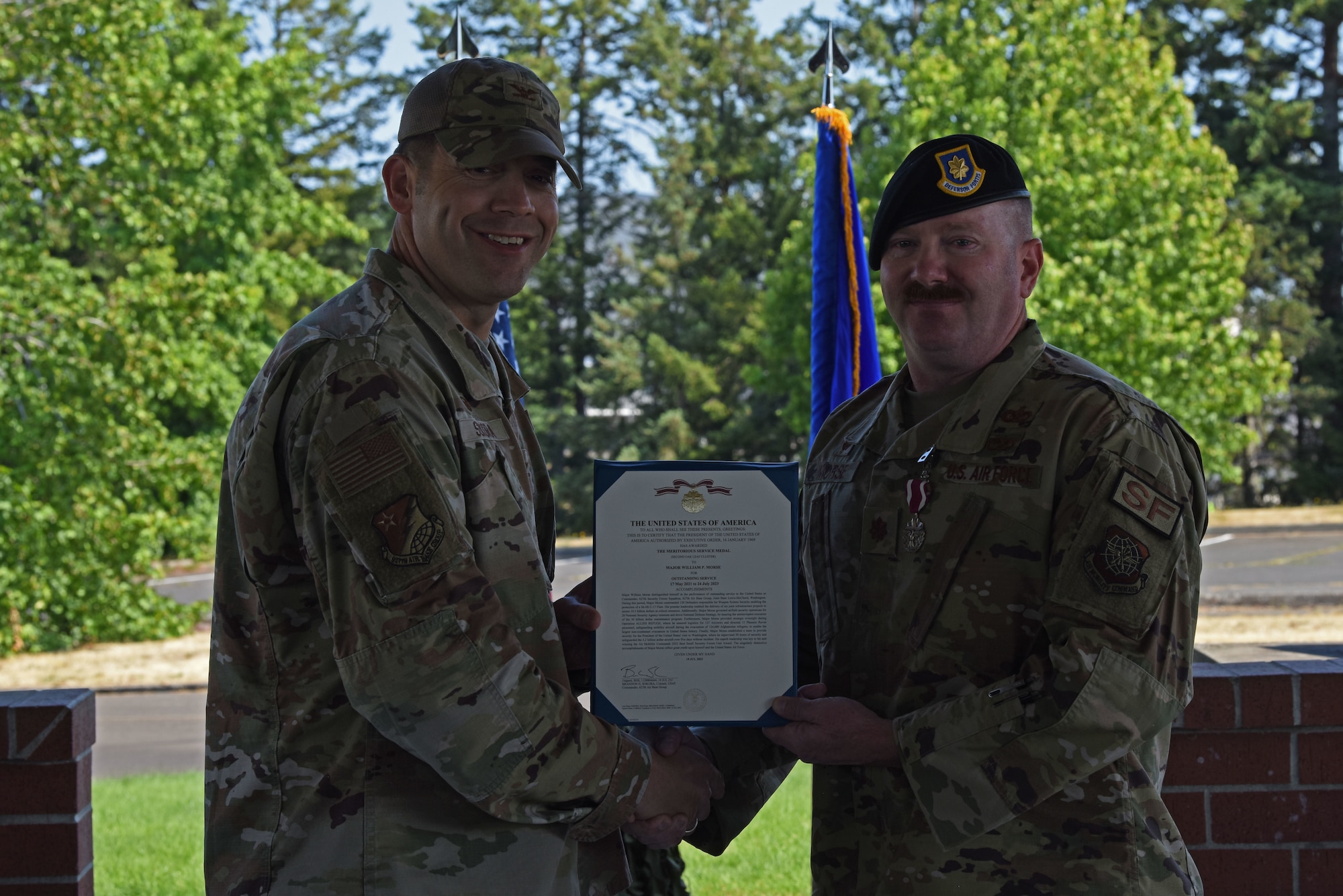 U.S. Air Force Col. Brandon Sokora, 627th Air Base Group commander, left, presents Maj. William Morse, outgoing 627th Security Forces commander, with a Meritorious Service Medal at the 627th SFS change of command ceremony at Joint Base Lewis-McChord, Washington, July 20, 2023. Morse served as commander of the 627th SFS for two years and under his command, the squadron received the 2022 Air Mobility Command Security Forces Squadron of the Year award. (U.S. Air Force photo by Staff Sgt. Zoe Thacker)